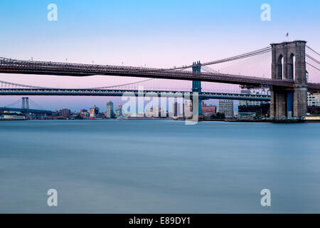 Brooklyn, Manhattan und Williamsburg Brücken während der blauen Stunde. Wie aus South Street Seaport in Lower Manhattan in New York City gesehen. Stockfoto