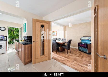 Ein Blick durch doppelte, solide Holz Türen aus einer Küche in ein Esszimmer in einem erweiterten & renovierten Haus, UK Stockfoto