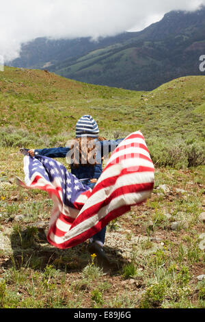 Mädchen in amerikanische Flagge im Feld gewickelt Stockfoto