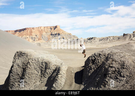 Junge, springen von Felsen in der Wüste Stockfoto