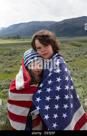 Bruder und Schwester gewickelt in amerikanische Flagge im Feld Stockfoto