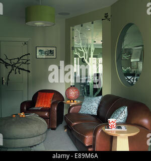 30er Jahre Stil Ledersofa und Sessel im Retro-Wohnzimmer mit graviertem Spiegel und kreisförmigen inneren Fenster Stockfoto