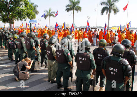 Phnom Penh, Kambodscha. 3. Oktober 2014. Buddhistische Mönche marschieren vorbei Aufruhr Polizisten vor dem Königspalast in Phnom Penh, Kambodscha, 3. Oktober 2014. Rund 100 buddhistische Mönche am Freitag marschierten in der Hauptstadt Phnom Penh inmitten Gerüchte, dass das Ministerium von Sekten und Religion hat ein Grundstück zu einem nahe gelegenen NagaWorld Hotel und Casino des ikonischen buddhistischen Instituts vermietet. Bildnachweis: Phearum/Xinhua/Alamy Live-Nachrichten Stockfoto