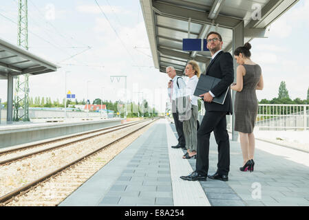 Vier Unternehmer warten auf Zug Stockfoto