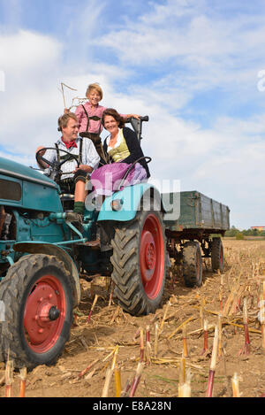 Familie auf Traktor im Kornfeld, Bayern, Deutschland Stockfoto