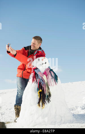 Mann unter Bild mit Ihrem Smartphone von ihm und Schneemann, Bayern, Deutschland Stockfoto