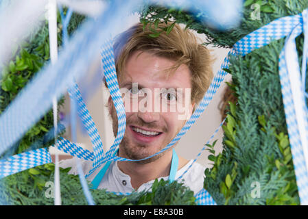 Mitte erwachsenen Mannes Blick durch Kranz Lächeln Stockfoto