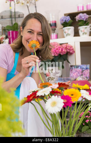 Porträt von Mitte Erwachsene Frau mit Blume, lächelnd Stockfoto