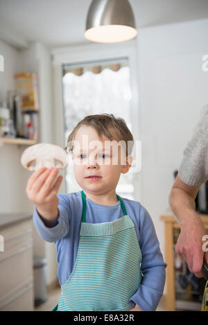 Junge mit Pilz Slice in Küche Stockfoto