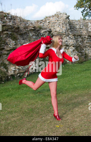 Weibliche Santa Sack von laufen präsentiert Santas Helfer auf eine Lieferung ausgeführt Stockfoto