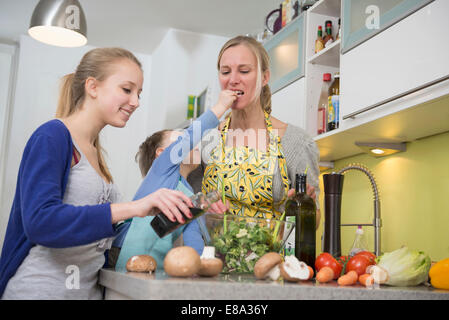 Mutter und Tochter Geschmack Salat während der Fütterung Mutter Sohn Stockfoto