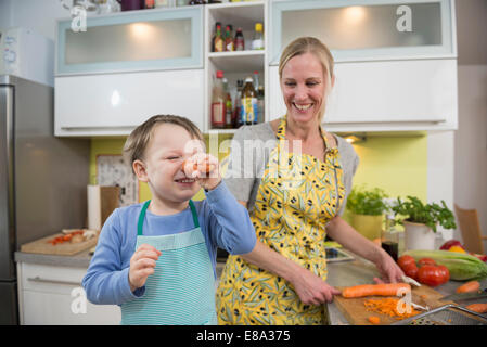 Junge Narren um mit Karotten, während Mutter zu lachen Stockfoto