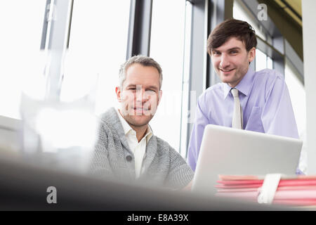 Geschäftsleute benutzen Laptop im Büro, lächeln Stockfoto