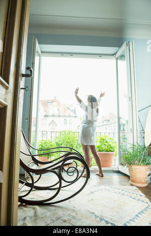 Ältere Frau dehnen ihren Körper in der Nähe von Fenster Stockfoto