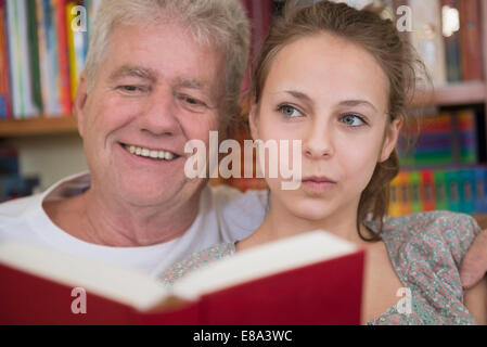 Großvater und Enkelin Lesebuch auf Couch im lebenden Raum, lächelnd Stockfoto