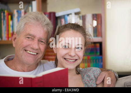 Großvater und Enkelin Lesebuch auf Couch im lebenden Raum, lächelnd Stockfoto