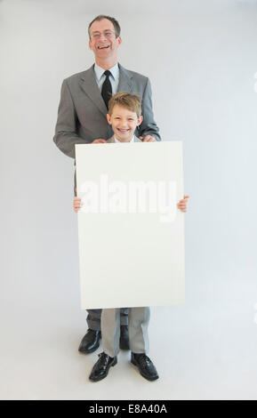 Vater und Sohn halten leeres Whiteboard, Lächeln, Porträt Stockfoto