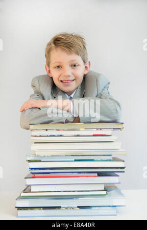 Porträt eines jungen stützte sich auf Bücherstapel, lächelnd Stockfoto