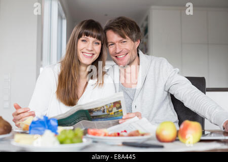 Porträt des Paares frühstücken und Zeitung lesen zusammen, Lächeln Stockfoto