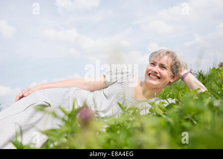 Reife Frau liegend auf Rasen, Lächeln Stockfoto