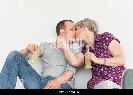 Älteres Paar küssen einander mit Trinkflasche Stockfoto