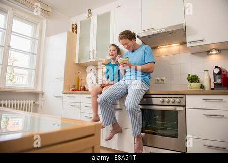 Vater und Sohn essen Müsli in Küche Stockfoto