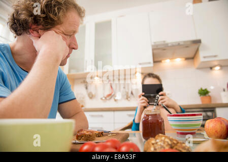 Vater Sohn Videospiel am Frühstückstisch zu betrachten Stockfoto