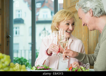 Älteres Paar am Tisch sitzen und Klirren der Gläser Sekt Wein, Lächeln Stockfoto