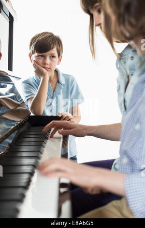 Mutter und Tochter spielt Klavier, während Bruder hören Stockfoto
