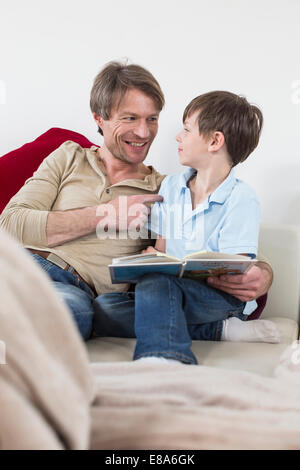 Vater und Sohn sitzen mit Buch, Lächeln Stockfoto