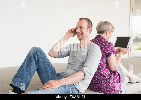 Reifer Mann sprechen auf Handy und Reife Frau mit digital-Tablette, Lächeln Stockfoto