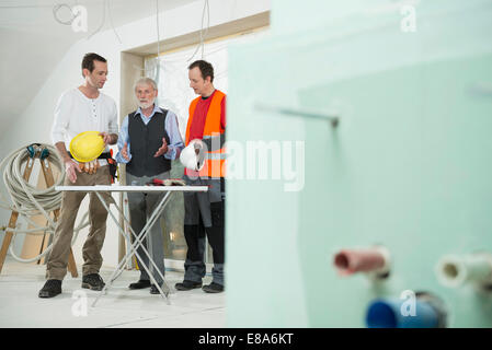 Architekt und zwei Bauarbeiter auf der Baustelle des Neubaus Stockfoto