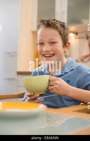 Porträt von lächelnden jungen Holding Cup in Küche Stockfoto