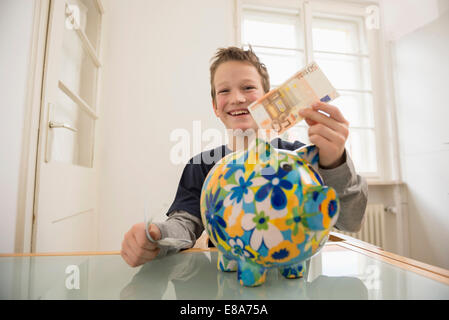 Lächelnde junge mit Sparschwein und 50-Euro-Schein Stockfoto