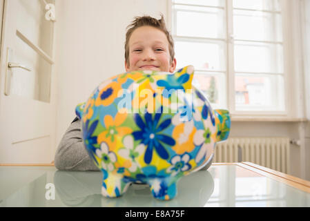 Lächelnde junge mit Sparschwein Stockfoto