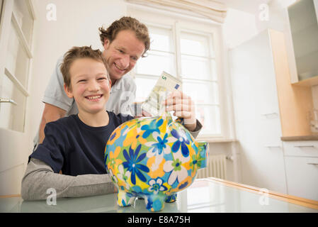 Vater und Sohn mit Sparschwein und 5 Euro-Schein Stockfoto