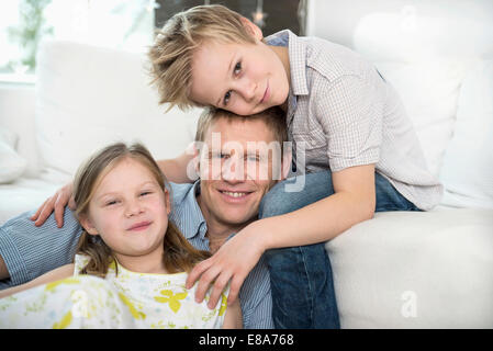 Vater sitzt auf der Couch mit Kindern Stockfoto