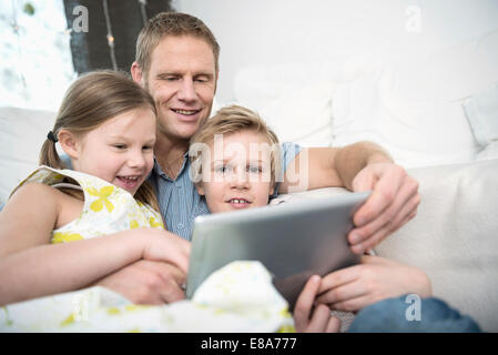 Vater mit Kindern auf Couch mit Tablet PC Stockfoto