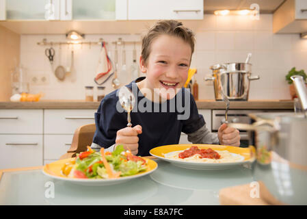 Lächelnde junge Essen Spaghetti und Salat Stockfoto