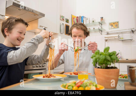 Vater und Sohn Essen Spaghetti und Salat in Küche Stockfoto