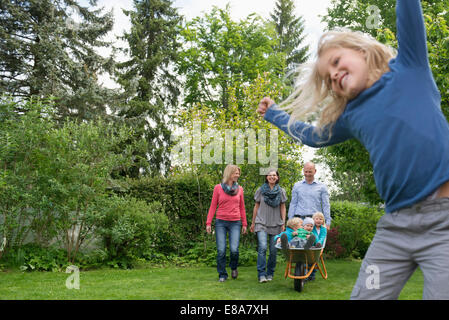 Junge Familie spielen im Garten mit Schubkarre Stockfoto