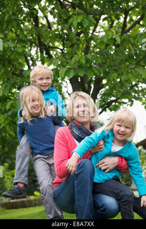 Huckepack-Mutter spielen Garten mit kleinen Kindern Stockfoto