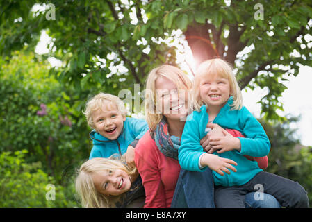 Mutter mit drei kleinen Kindern im Garten spielen Stockfoto