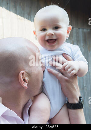 Vater hält Baby Sohn stolz Lachen glücklich Stockfoto