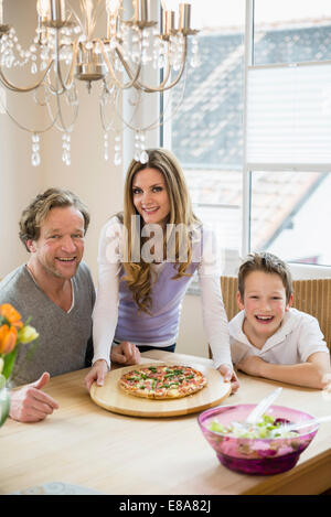 Familie zu Hause essen Pizza und Salat Stockfoto