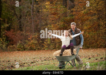 Vater schob glückliche Tochter in Schubkarre Stockfoto