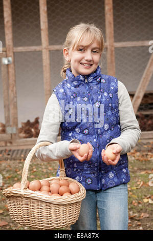 Blondes Mädchen mit Korb mit Eiern auf Bauernhof Stockfoto