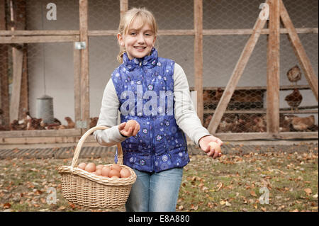 Blondes Mädchen mit Korb mit Eiern auf Bauernhof Stockfoto