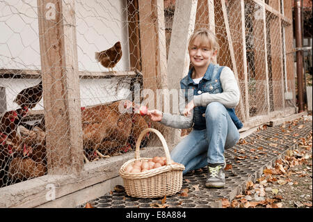 Mädchen am Bio-Bauernhof Hühner füttern Stockfoto