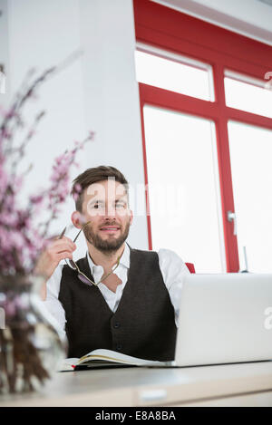 Junger Geschäftsmann Büro lächelnd Porträt Gläser Stockfoto